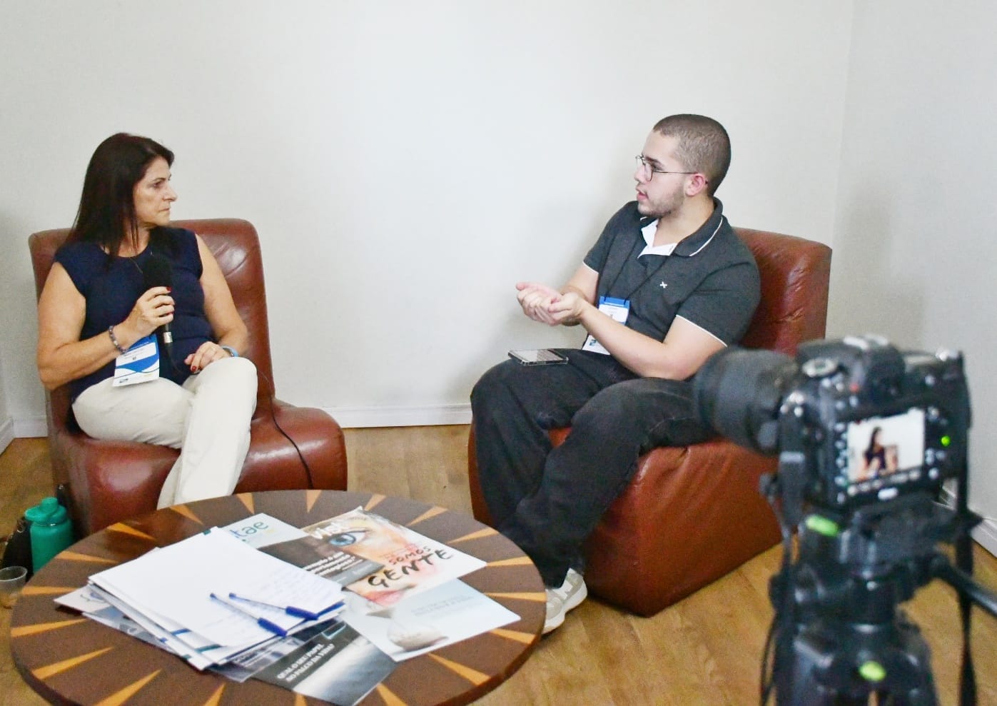 Cristina Lo Sardo psicóloga especialista em dependência química sentada com um microfone na mão dando entrevista à agenzia