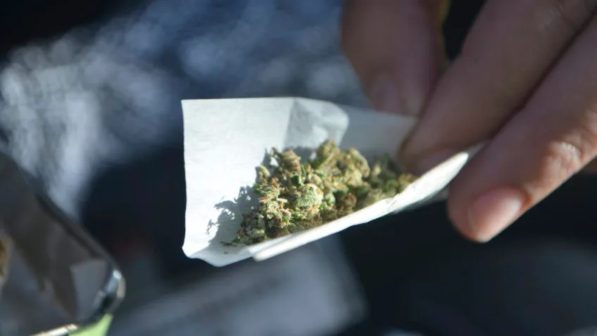 Close-up de mãos preparando um cigarro de maconha