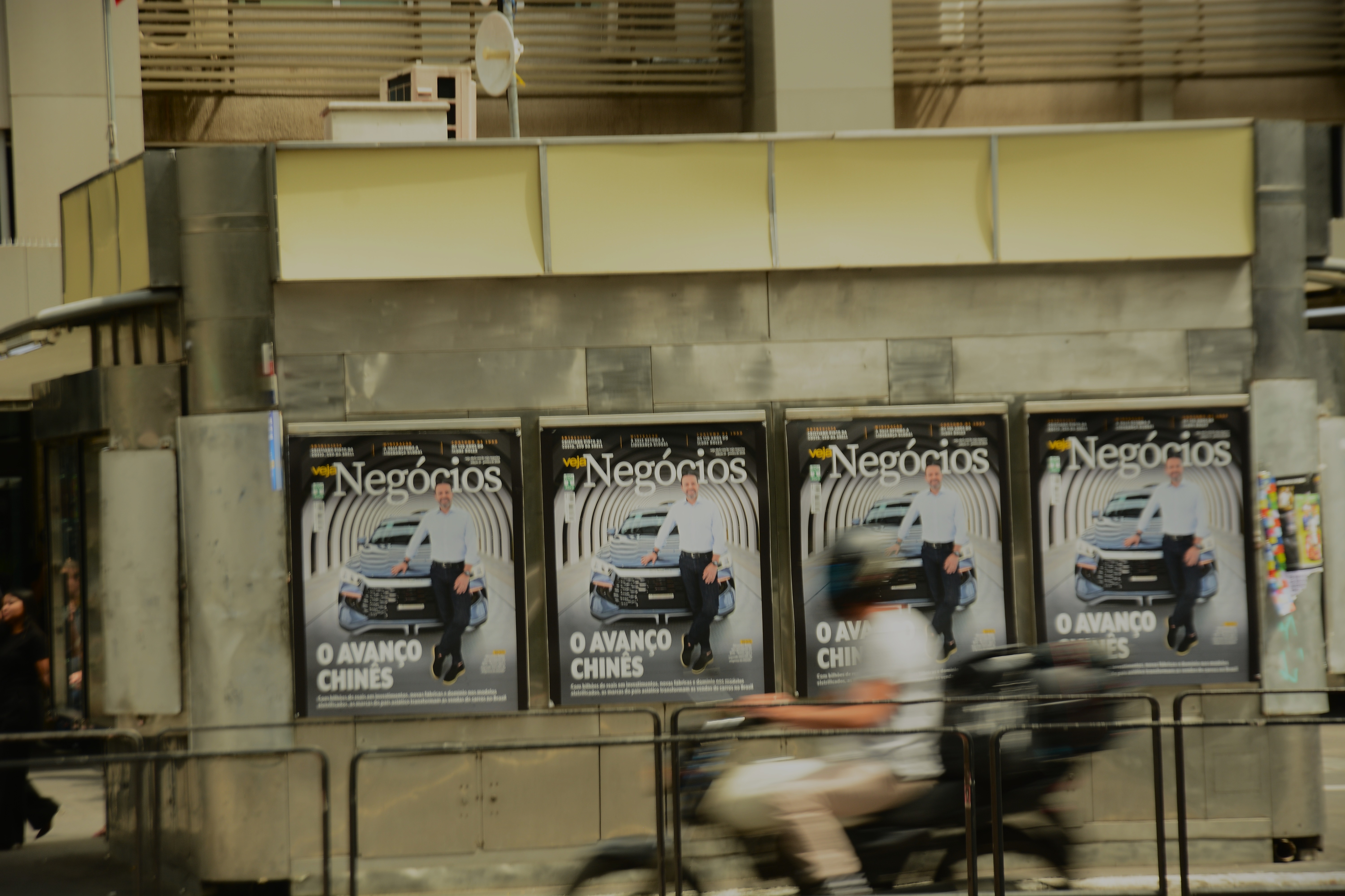 Um motoqueiro passa na frente de anúncios de uma revista de negócios em uma banca de jornal - Foto: Heitor Landim / Agenzia