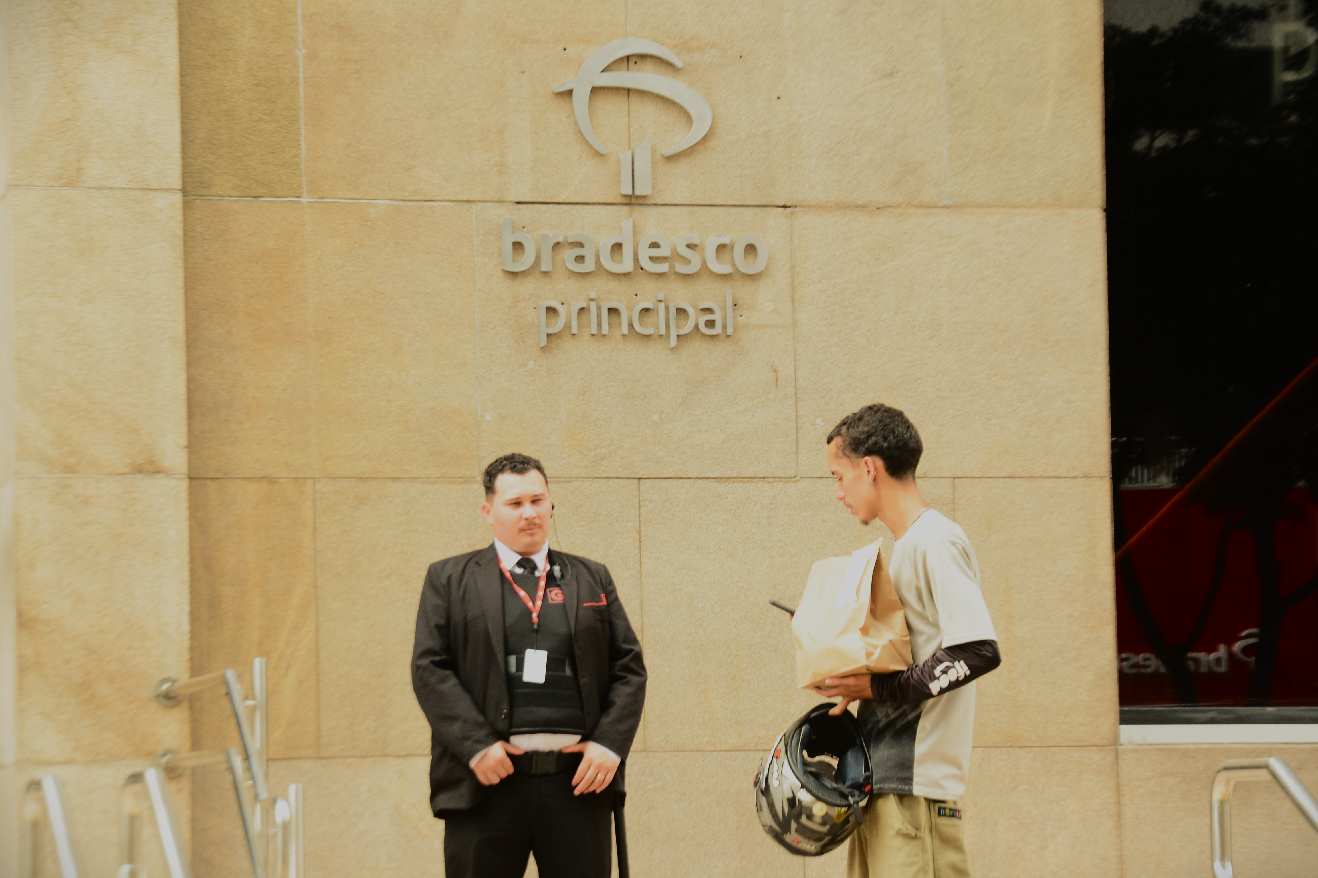 Um segurança observa um motoboy na frente do Prédio Principal do Banco Bradesco - Foto: Heitor Landim / Agenzia