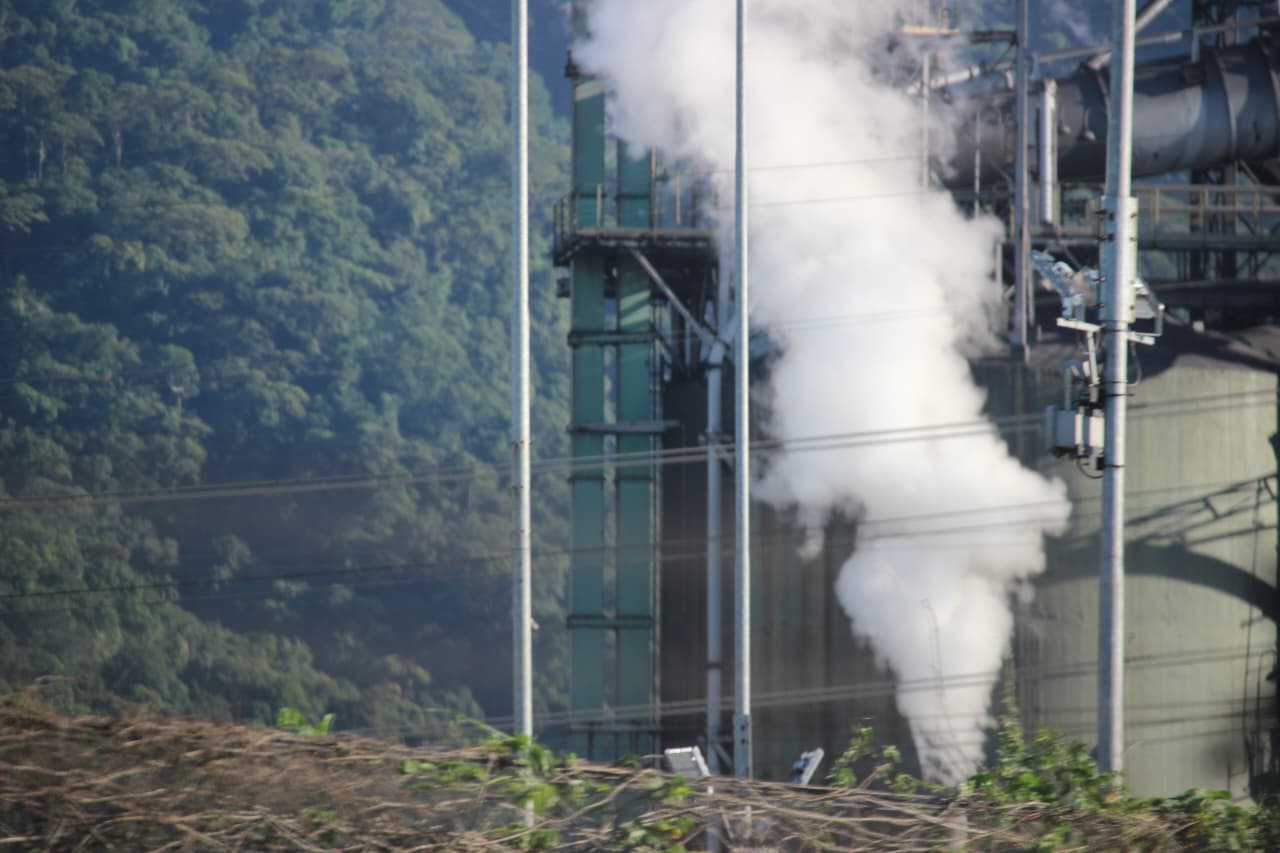 Imagem de uma fábrica exalando uma fumaça branca, gerando uma maior poluição da atmosfera.
