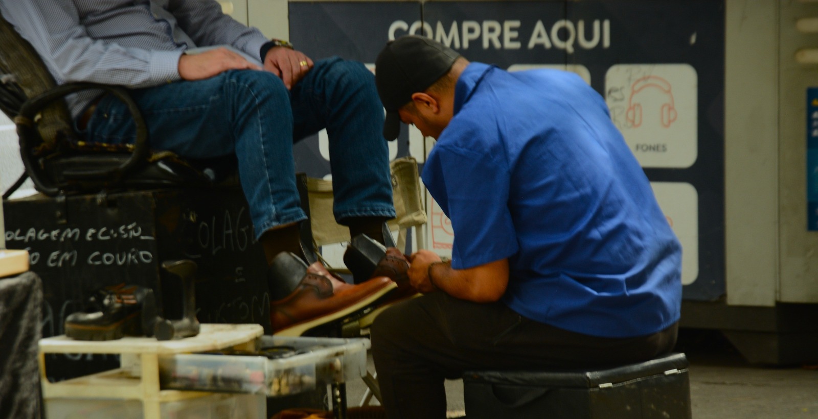 Um engraxate lustrando os sapatos de um homem em trajes sociais. Foto por: Heitor Landim / Agenzia