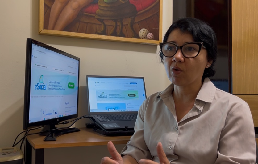 Kátia Piauy (cabelo curto, óculos) está em frente a um computador dando entrevista à Agenzia sobre a importância de conhecer os direitos trabalhistas