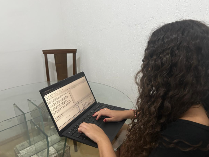 Mulher jovem de costas para câmera olhando para um computador com sistema de software